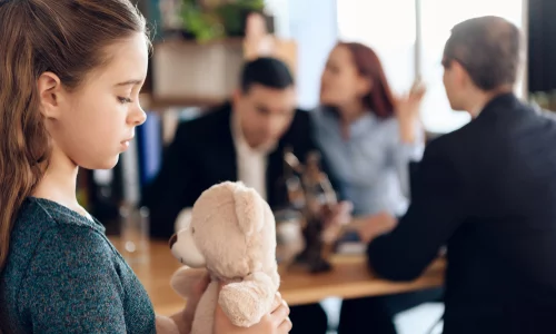 Parents discuss divorce details with a lawyer as their child looks on, a sad witness to the conversation that will reshape their family dynamics.