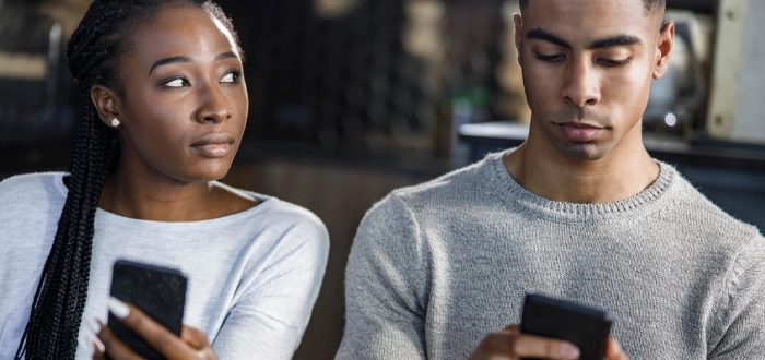 Woman looking at her partner's phone with a concerned expression