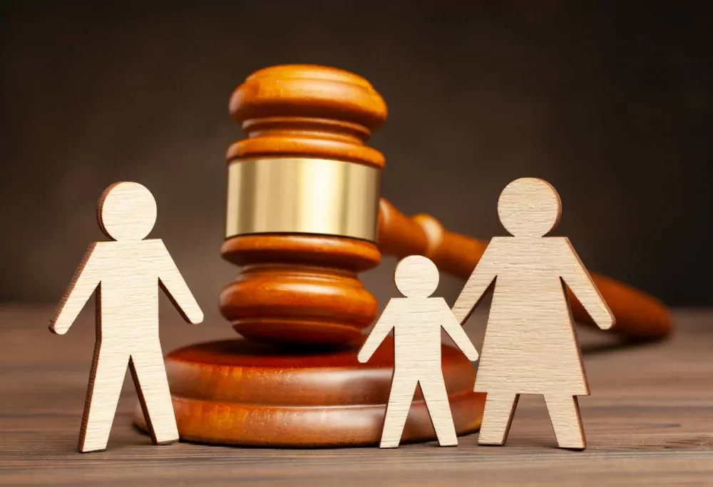 An illustration of a gavel alongside paper figures of parents and a child represents the various factors influencing child support decisions.