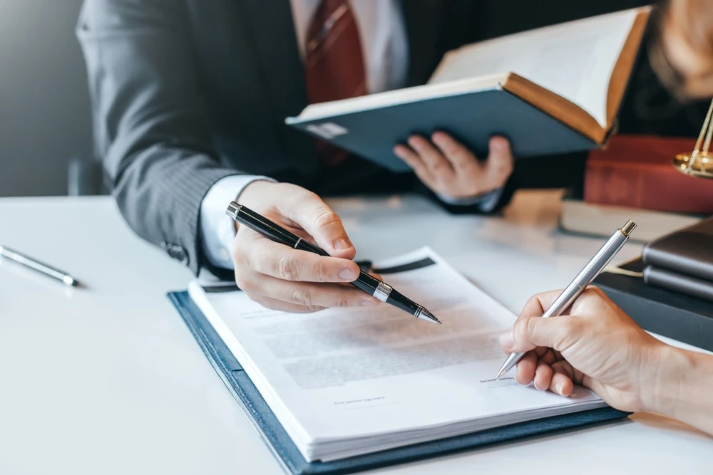 A client signs legal papers at a law office, symbolizing proactive measures to reduce the likelihood of alimony or spousal maintenance payments.