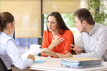 A couple actively engages with a lawyer in an office, representing mediation as a constructive alternative to litigation.