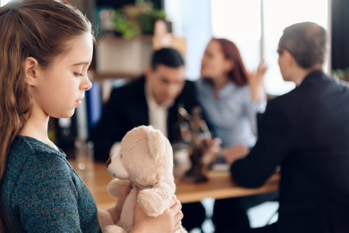 Parents sit with their child and legal papers in a lawyer's office, discussing the details of a Joint Managing Conservatorship arrangement.