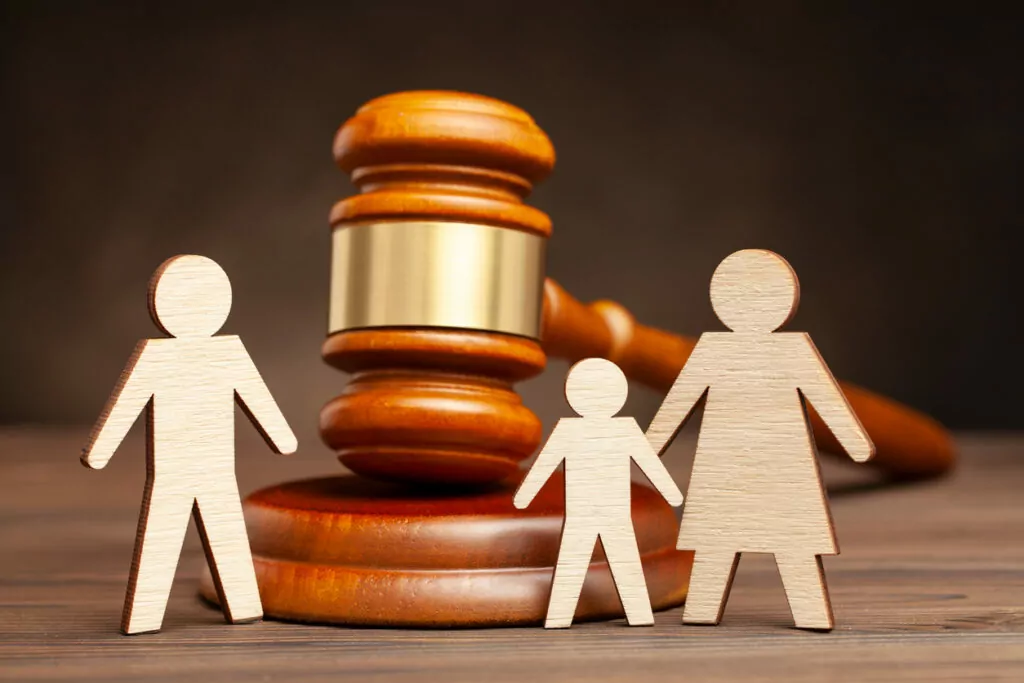 Parents sit with their child and legal papers in a lawyer's office, discussing the details of a Joint Managing Conservatorship arrangement.