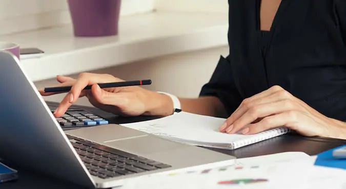 A person works intently with financial documents and a laptop, representing the critical financial considerations involved in family law enforcement cases.