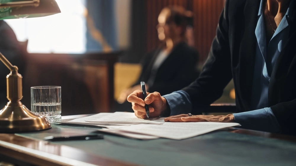 A family lawyer sits alongside a client in a courtroom, representing the dedicated legal representation provided by an enforcement lawyer.