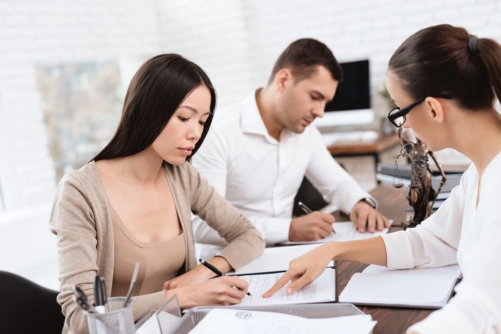 A divorcing couple signs documents at a lawyer's office, representing mutual consent divorce in Texas