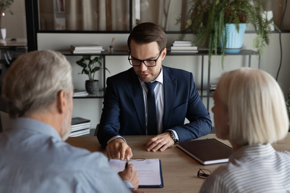 A couple sits in a lawyer's office, discussing the division of retirement accounts and pensions, a crucial aspect of their divorce settlement.