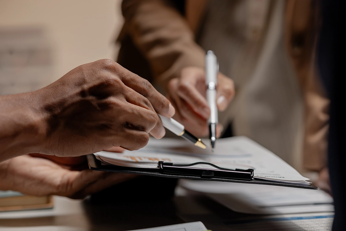order modification two hands pointing at document with a pen